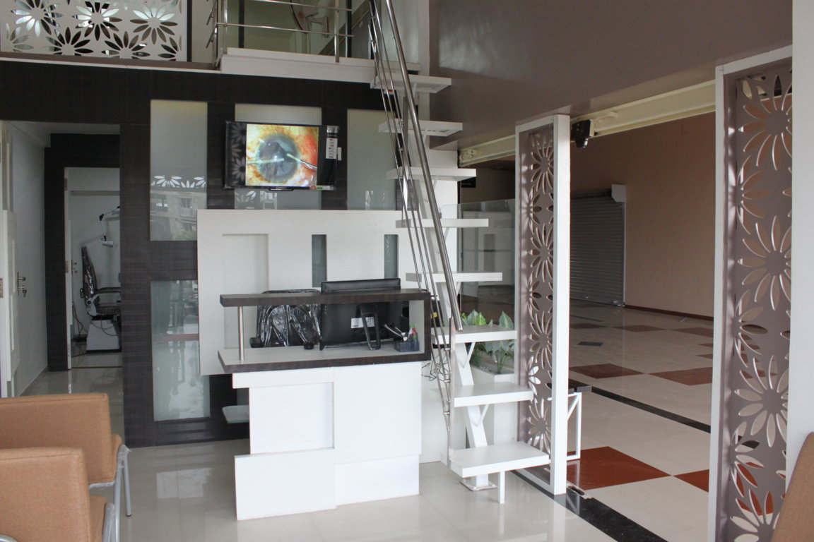 Insight Institute reception counter framed by laser-cut botanical panels with a live cataract surgery feed playing on the wall-mounted screen